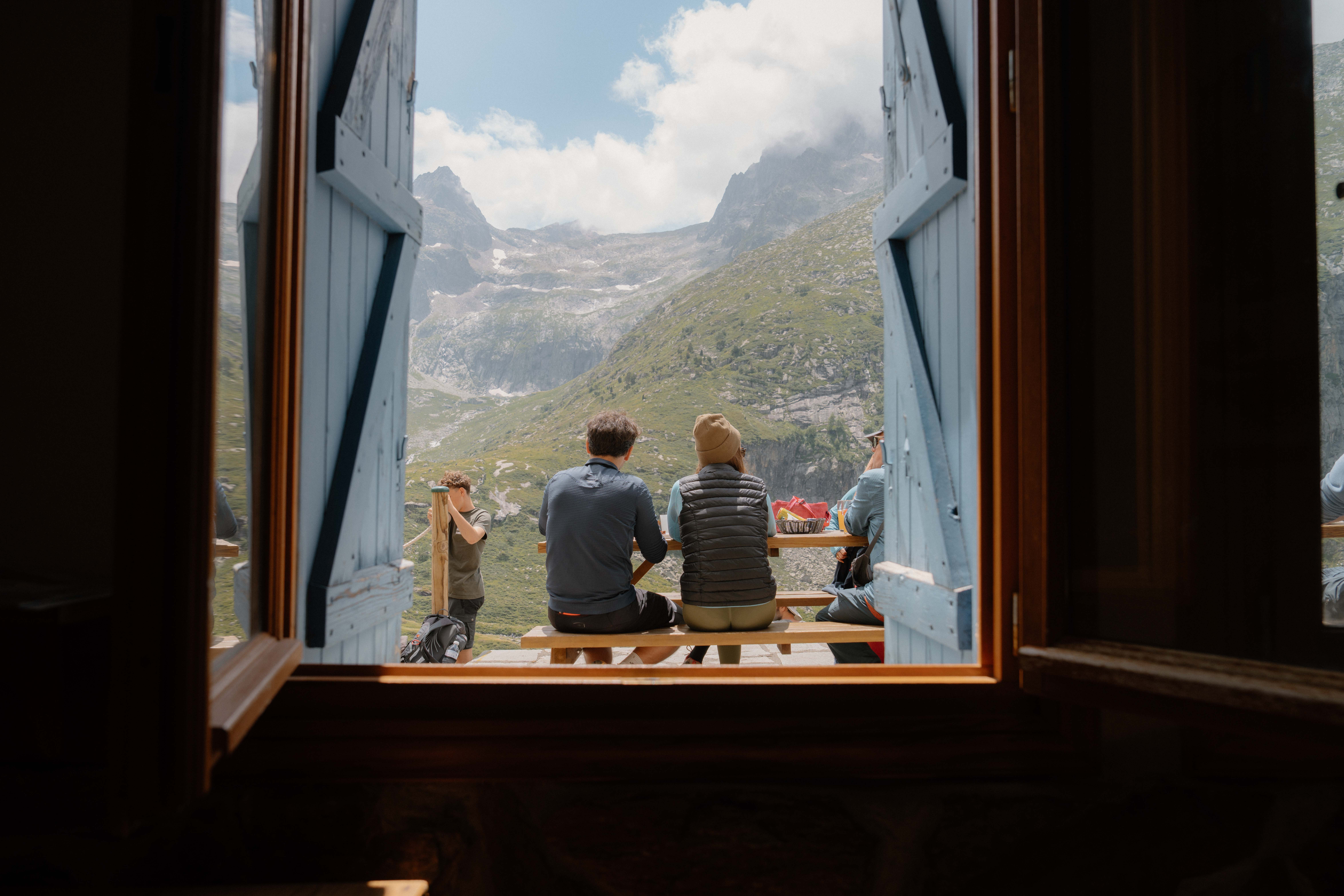 Two people look out of a window over a rocky mountain range